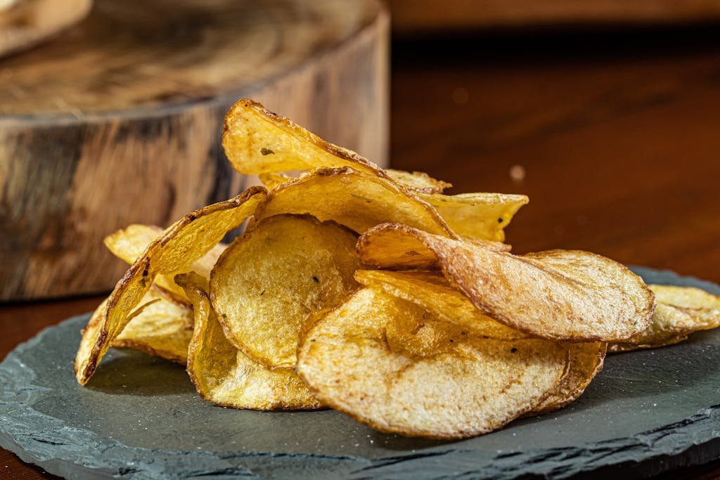 Delicious homemade potato chips displayed on a rustic slate plate.