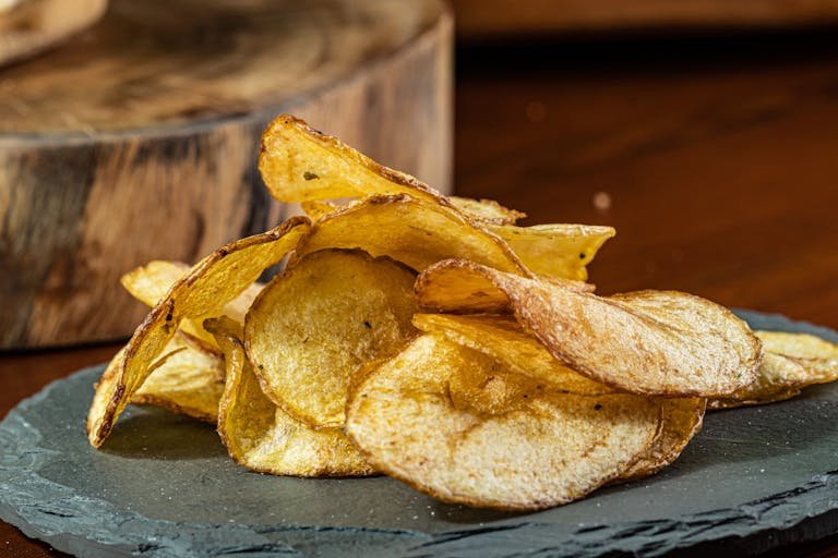 Delicious homemade potato chips displayed on a rustic slate plate.